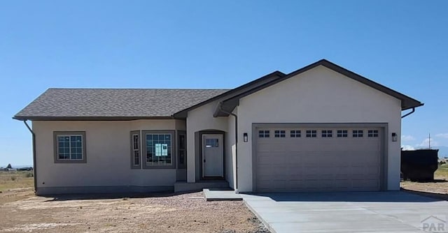 ranch-style home featuring an attached garage, driveway, and stucco siding