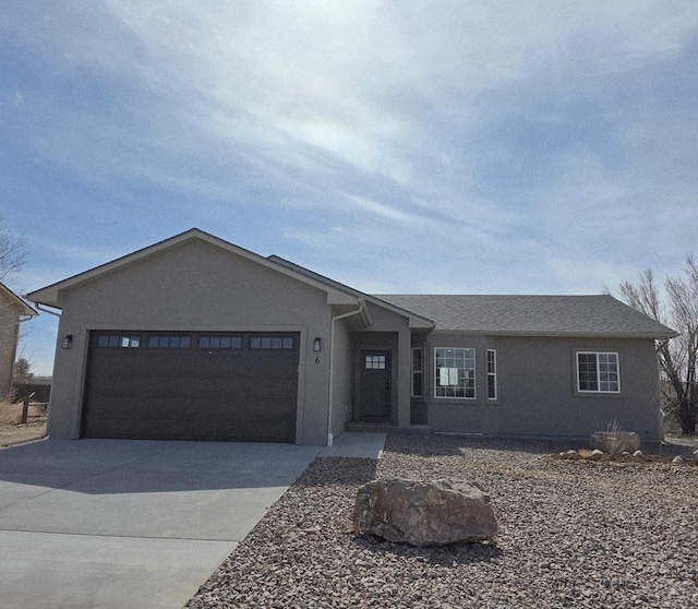 ranch-style house featuring stucco siding, an attached garage, and driveway