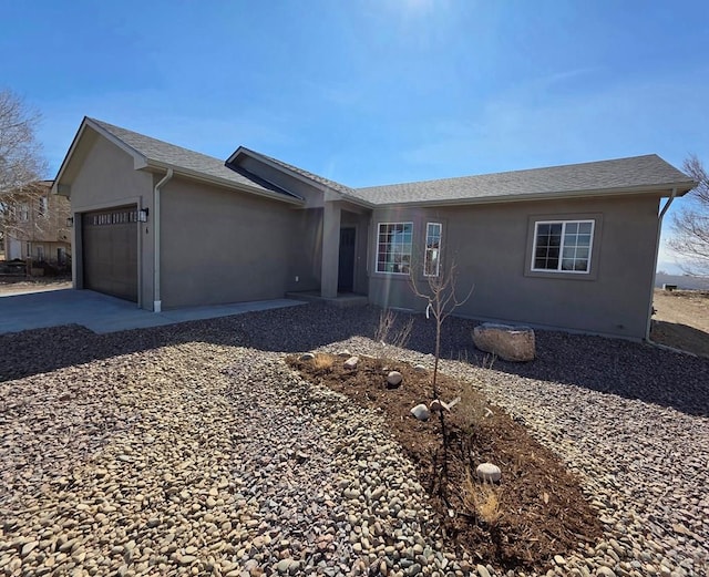 ranch-style house featuring stucco siding, an attached garage, concrete driveway, and a shingled roof