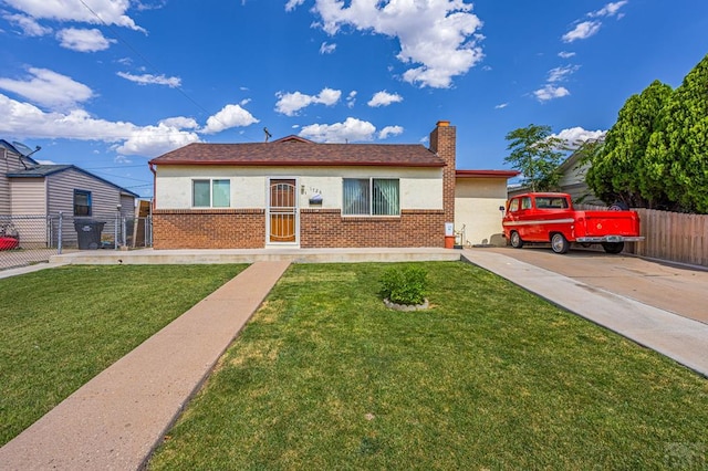 ranch-style house with brick siding, a chimney, stucco siding, fence, and a front lawn