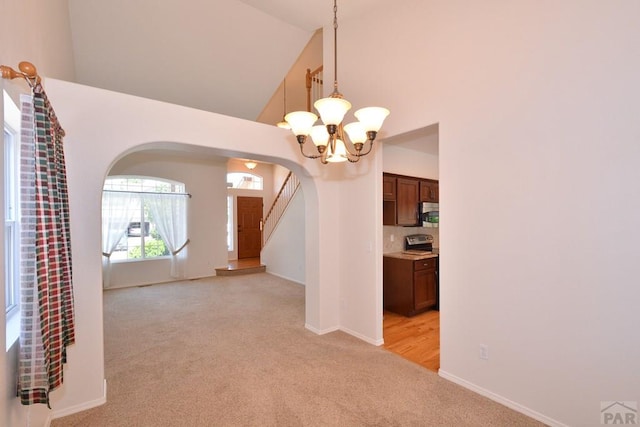 1135 Mount Estes Dr, Colorado Springs, CO 80921 - unfurnished dining area with arched walkways, light colored carpet, a chandelier, high vaulted ceiling, and stairway