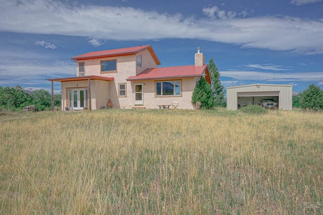 view of front of home with metal roof, a chimney, and stucco siding