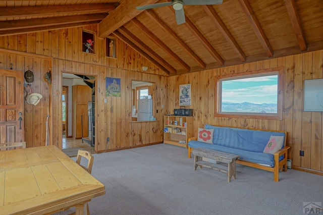 sitting room featuring wooden walls, light colored carpet, wood ceiling, ceiling fan, and vaulted ceiling with beams