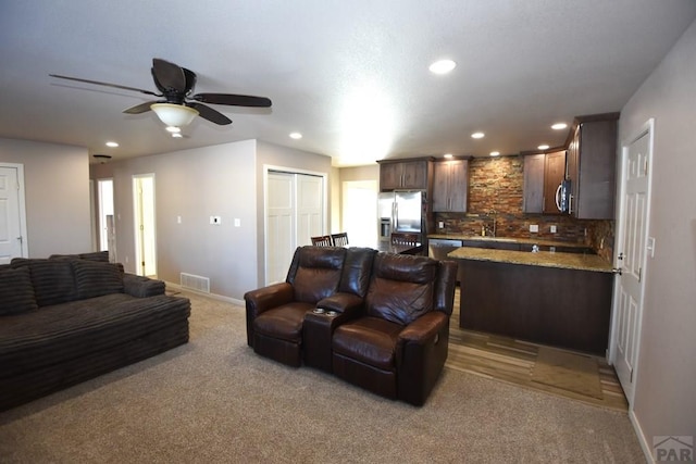 living area featuring visible vents, baseboards, recessed lighting, ceiling fan, and light colored carpet