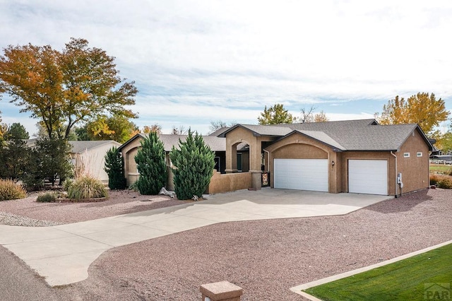 view of front of house featuring driveway, an attached garage, and stucco siding