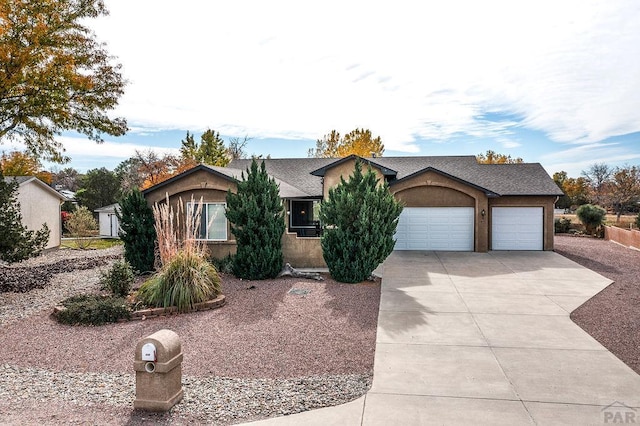 view of front of house with driveway, roof with shingles, an attached garage, and stucco siding