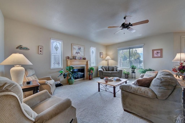 living room featuring carpet floors, a fireplace with flush hearth, and a ceiling fan