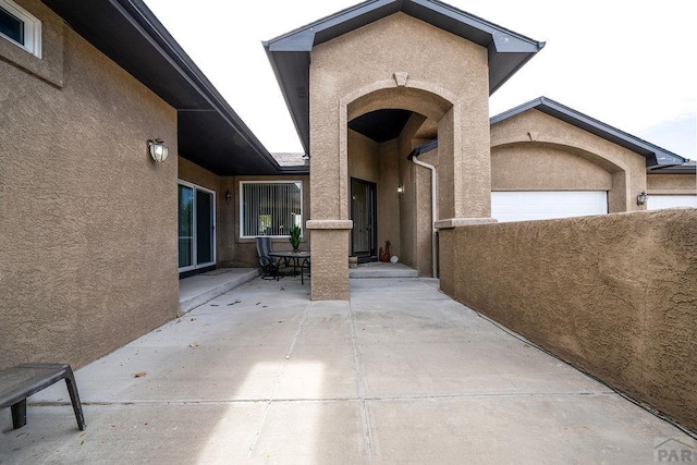 entrance to property featuring outdoor dining area, a patio, and stucco siding