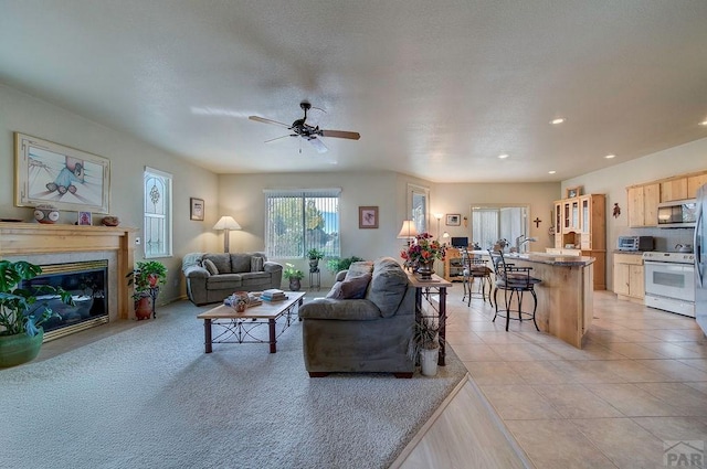 living room with light tile patterned floors, ceiling fan, a fireplace, and recessed lighting