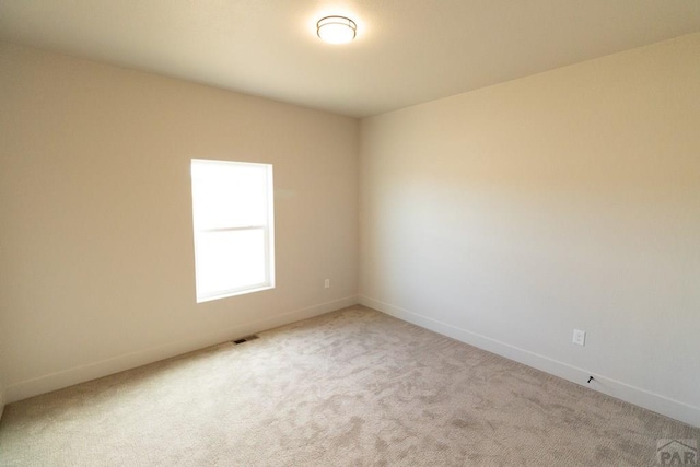 carpeted spare room featuring baseboards and visible vents