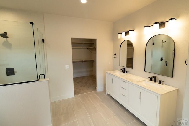 full bath featuring double vanity, a sink, a walk in closet, and a shower stall