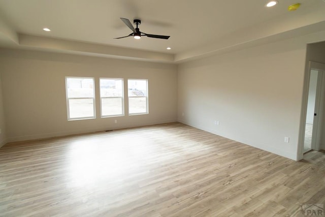 unfurnished room featuring a tray ceiling, light wood-style flooring, and recessed lighting