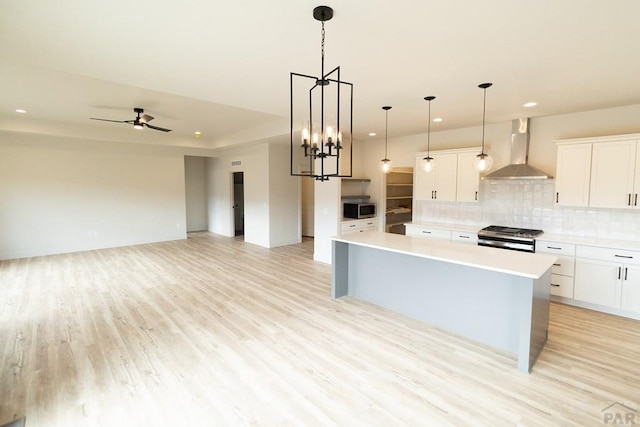 kitchen with appliances with stainless steel finishes, backsplash, light countertops, and wall chimney range hood