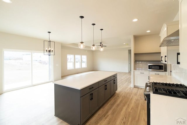 kitchen with appliances with stainless steel finishes, light countertops, light wood-style floors, and under cabinet range hood