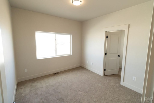 carpeted empty room featuring visible vents and baseboards