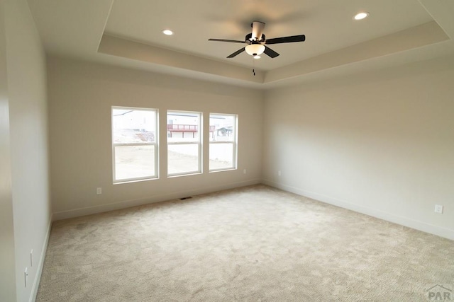 carpeted spare room featuring recessed lighting, a raised ceiling, and baseboards