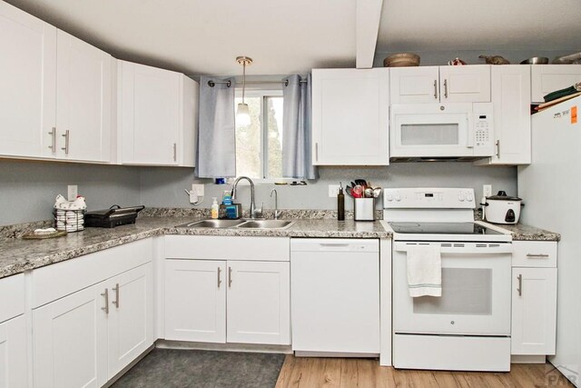 1710 E 3rd St, Pueblo, CO 81001 - kitchen with white appliances, light wood-style flooring, white cabinetry, a sink, and hanging light fixtures
