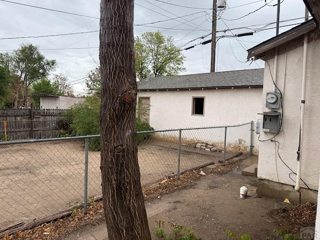 exterior space featuring stucco siding, roof with shingles, and fence