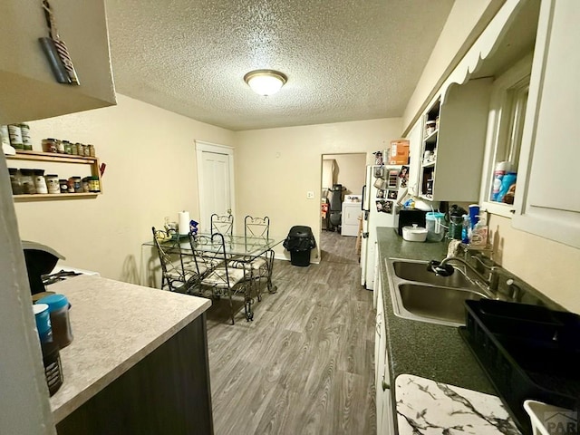 kitchen featuring a sink, light wood finished floors, a textured ceiling, and open shelves