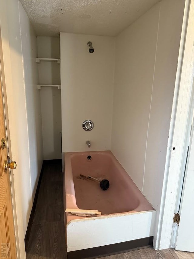 full bath featuring wood finished floors, a washtub, baseboards, and a textured ceiling