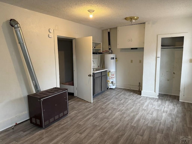 interior space with water heater, a textured ceiling, wood finished floors, and baseboards