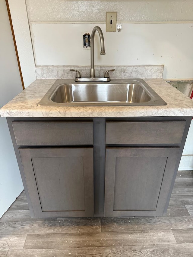 kitchen featuring light countertops, gray cabinets, wood finished floors, and a sink