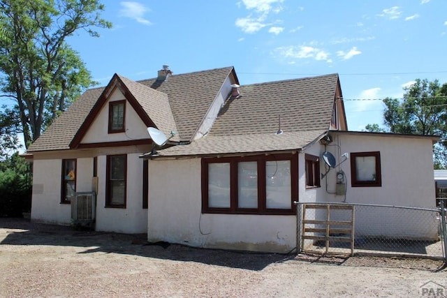 view of front of house featuring stucco siding, roof with shingles, and fence