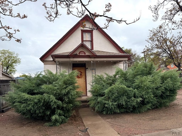 view of front facade with a porch, fence, and stucco siding