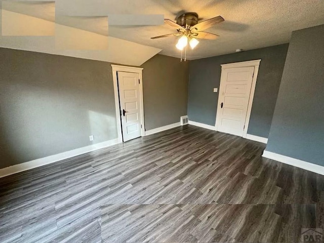 empty room with dark wood-style floors, baseboards, visible vents, and ceiling fan