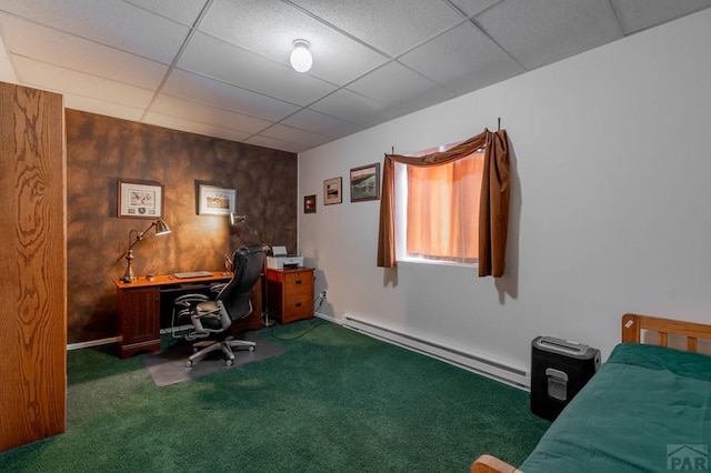 office area with dark colored carpet, a drop ceiling, wood walls, and baseboard heating