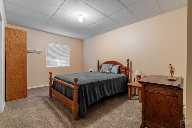 carpeted bedroom with a paneled ceiling and baseboards