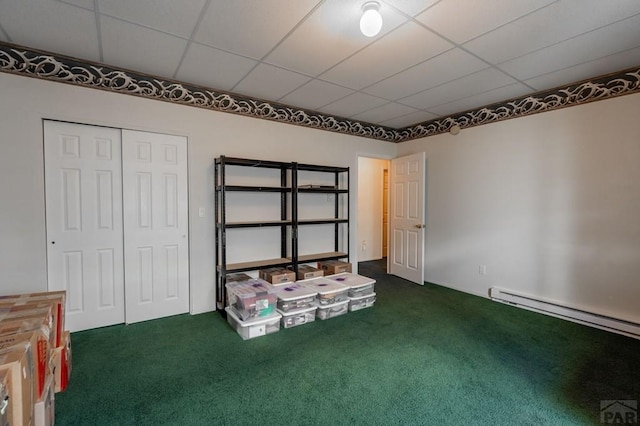 interior space featuring a closet, dark carpet, baseboard heating, and a drop ceiling