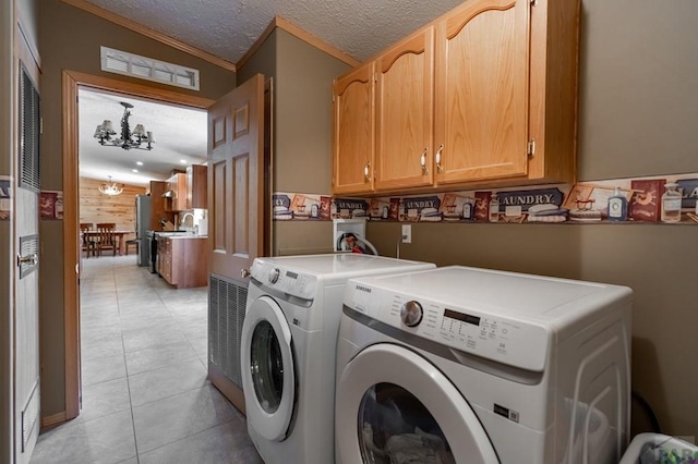 washroom with a textured ceiling, a chandelier, light tile patterned flooring, separate washer and dryer, and cabinet space