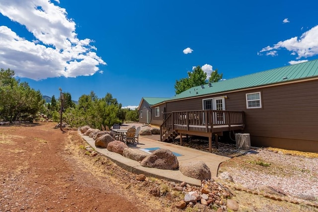 back of property featuring metal roof, a patio, and a wooden deck