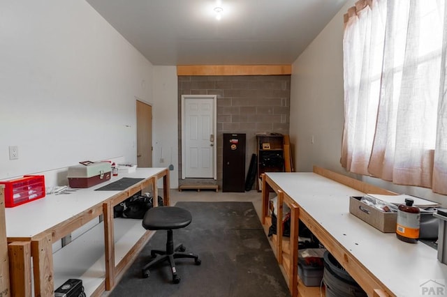 office space featuring concrete block wall, concrete floors, and a workshop area