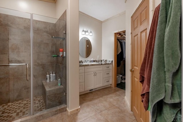 bathroom featuring tile patterned flooring, vanity, a spacious closet, ornamental molding, and a stall shower