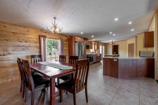 dining area featuring light tile patterned floors, plenty of natural light, a textured ceiling, and a notable chandelier