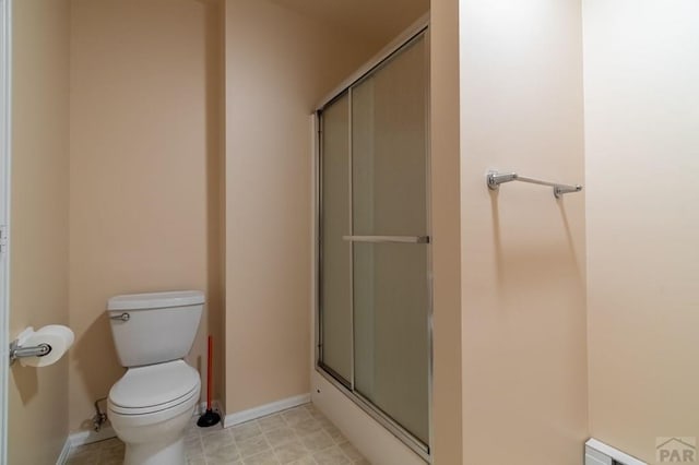 bathroom featuring a stall shower, baseboards, toilet, and a baseboard radiator