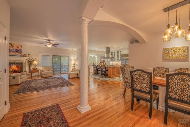 dining room featuring light wood-type flooring, visible vents, ceiling fan, and ornate columns