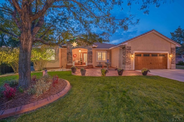 ranch-style house with a garage, driveway, a lawn, stone siding, and stucco siding