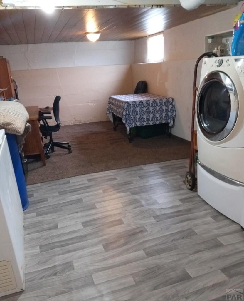 clothes washing area featuring light wood-type flooring, washer / clothes dryer, concrete block wall, and laundry area