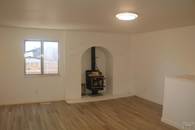 33 Regency Blvd, Pueblo, CO 81005 - unfurnished room featuring a wood stove, light wood-style flooring, and arched walkways