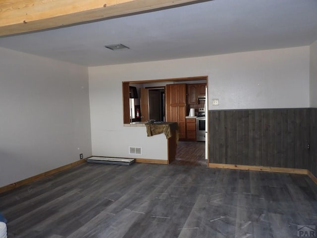 unfurnished room with visible vents, dark wood-style flooring, wood walls, and wainscoting