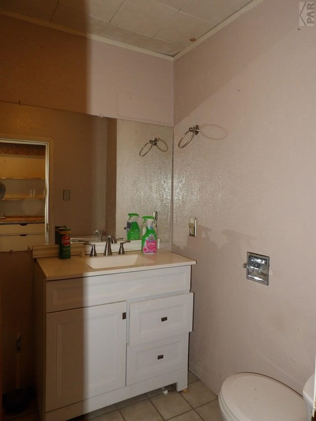 half bath featuring toilet, vanity, and tile patterned flooring