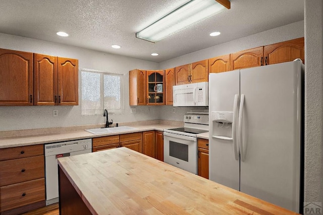 228 S Caddoa Dr, Pueblo West, CO 81007 - kitchen with white appliances, a sink, a textured ceiling, glass insert cabinets, and butcher block counters