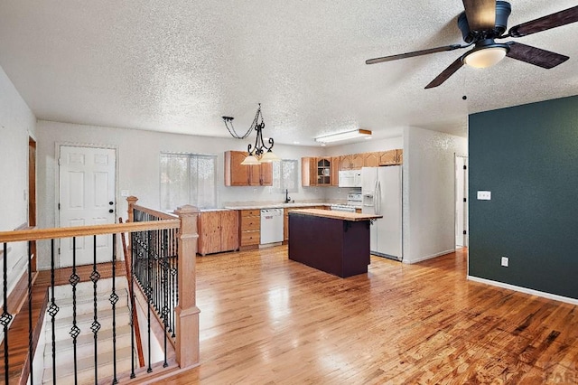 228 S Caddoa Dr, Pueblo West, CO 81007 - kitchen with white appliances, a kitchen island, light countertops, a textured ceiling, and light wood-style flooring