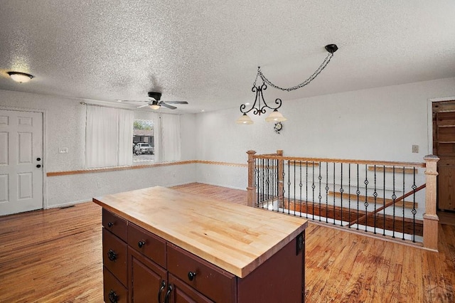 228 S Caddoa Dr, Pueblo West, CO 81007 - kitchen with butcher block countertops, a textured ceiling, light wood-type flooring, a ceiling fan, and a textured wall
