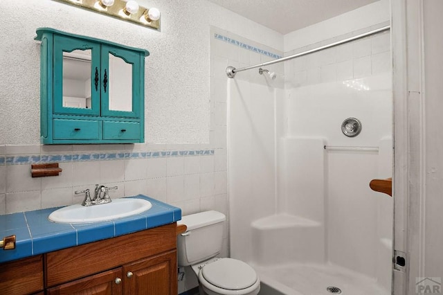 228 S Caddoa Dr, Pueblo West, CO 81007 - bathroom featuring a stall shower, toilet, vanity, tile walls, and wainscoting