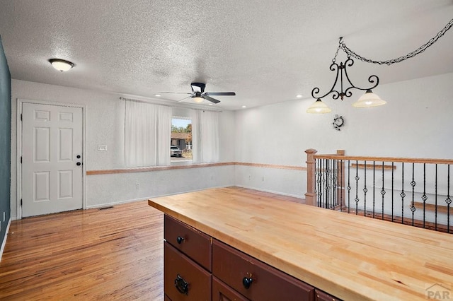 228 S Caddoa Dr, Pueblo West, CO 81007 - kitchen with butcher block countertops, a ceiling fan, a textured ceiling, light wood-type flooring, and decorative light fixtures