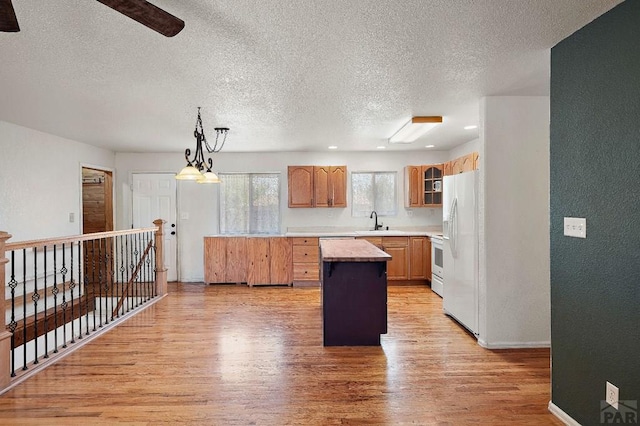 228 S Caddoa Dr, Pueblo West, CO 81007 - kitchen featuring white fridge with ice dispenser, a sink, light wood-type flooring, a textured ceiling, and glass insert cabinets